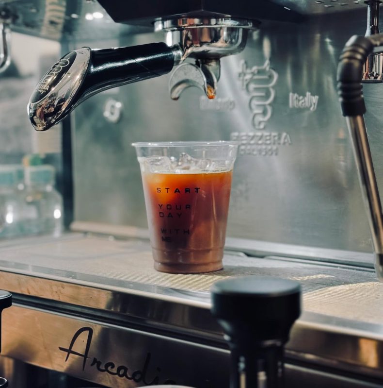 Espresso mengalir dari mesin Arcadia ke gelas berisi es bertuliskan Start your day with me